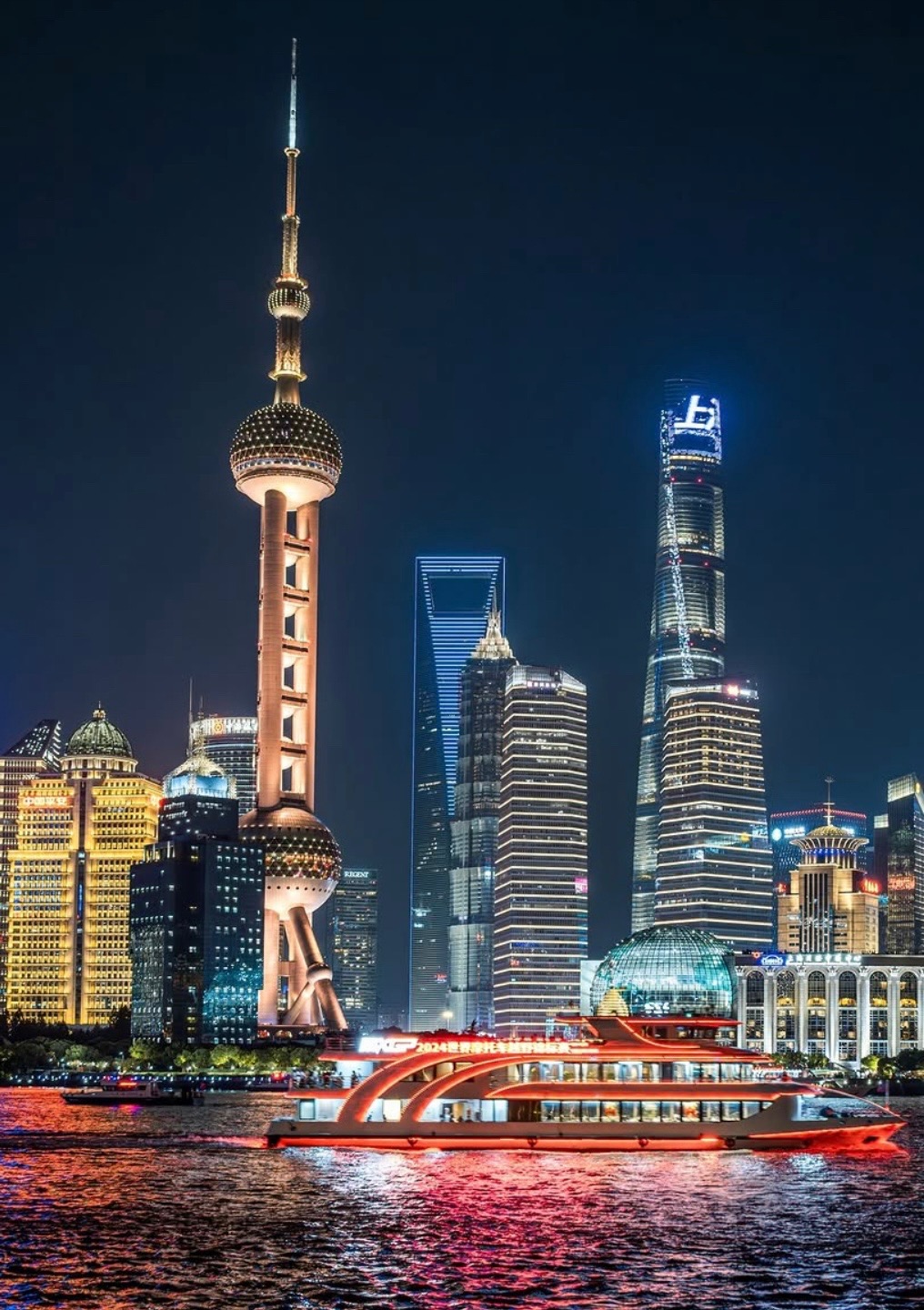 Shanghai's Pudong skyline at night, with the Oriental Pearl Tower and the Huangpu River